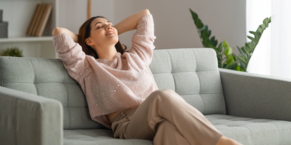 Frau auf einem Sofa ist zur inneren Ruhe gekommen und lächelt